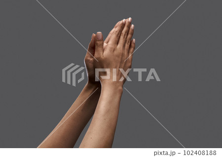 Female hands showing gesture of praying against grey background. Social issues, freedom of speech, equality 102408188