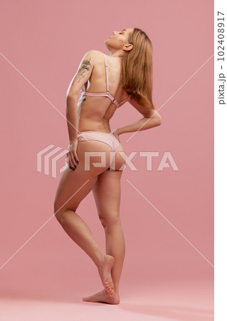 Back view portrait of young adorable model, girl with silk shine hair wearing swimsuit standing over pink studio background. Spa procedures Back view portrait of young adorable model, girl with silk shine hair wearing swimsuit standing over pink studio background. Spa procedures 102408917