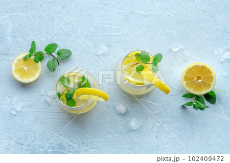 Lemonade with mint. Lemon water drink with ice. Two glasses and lemons 102409472