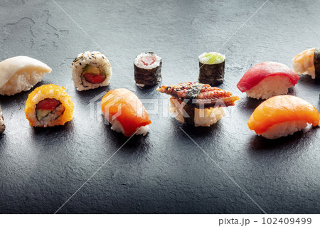 Sushi on a black slate plate. Nigiri with eel, salmon and tuna, roll etc 102409499