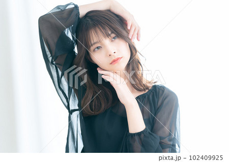 リビングの窓際でスキンケアをする若い女性 102409925