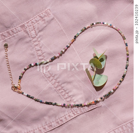 hippie style seed beads necklace. multicolored choker on a pink denim shirt with eucalyptus branch in a pocket. hippie style seed beads necklace. multicolored choker on a pink denim shirt with eucalyptus branch in a pocket. 102410239
