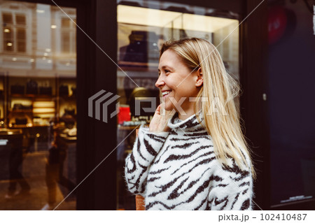 Waist up side portrait blonde woman smiling while walking around the city shopping  102410487