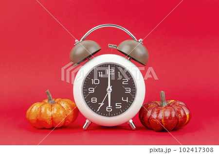The Vintage alarm clock with autumn pumpkins on red background. 102417308