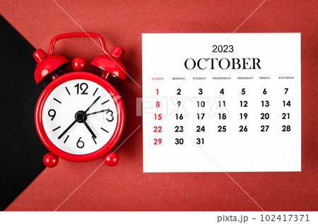 The October 2023 Monthly calendar year with alarm clock on red and black background. The October 2023 Monthly calendar year with alarm clock on red and black background. 102417371
