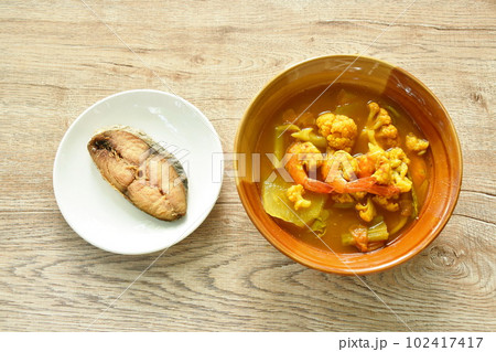 boiled shrimp and mixed vegetable in spicy and sour curry soup on bowl eat couple chop fried salty dry Indo-Pacific king mackerel fish on plate boiled shrimp and mixed vegetable in spicy and sour curry soup on bowl eat couple chop fried salty dry Indo-Pacific king mackerel fish on plate 102417417