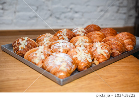 Sprinkle the finished croissants on a baking sheet with almond flakes 102419222