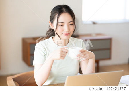 コーヒーを飲みながらパソコンを見る若い女性 コーヒーを飲みながらパソコンを見る若い女性 102421327
