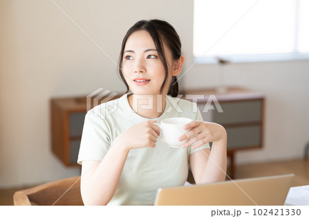 コーヒーを飲みながらパソコンを見る若い女性 コーヒーを飲みながらパソコンを見る若い女性 102421330