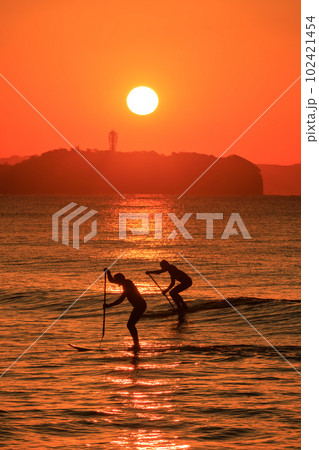 神奈川_江の島灯台の朝日とマリンスポーツを楽しむ人々 102421454