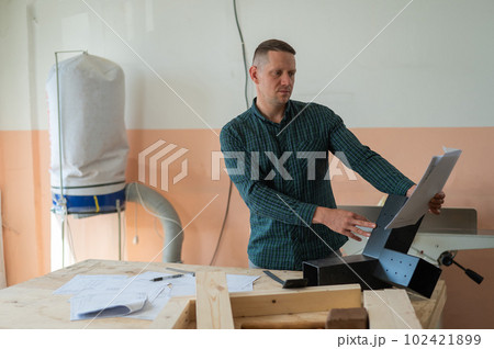 Caucasian man assembles furniture in the workshop and looks at the instructions.  102421899