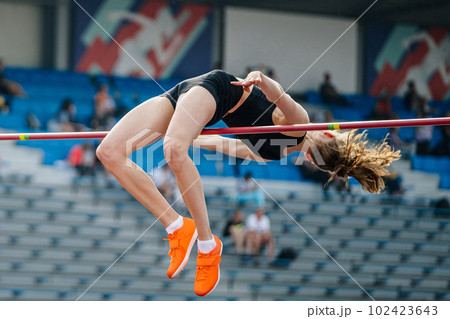 young woman jumper high jump in summer athletics championships, fosbury flop technique 102423643