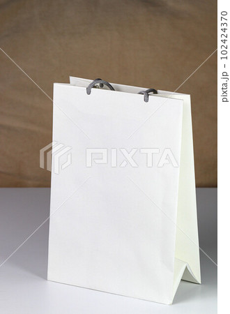 White paper shopping bag, present bag standing on white table with shallow focus. White paper shopping bag, present bag standing on white table with shallow focus. 102424370
