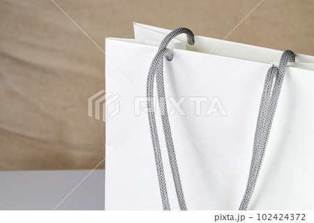 White paper shopping bag, present bag standing on white table with shallow focus. White paper shopping bag, present bag standing on white table with shallow focus. 102424372