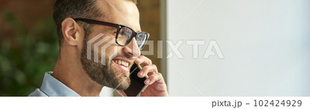 Mirthful man enjoying pleasant conversation and smiling Mirthful man enjoying pleasant conversation and smiling 102424929