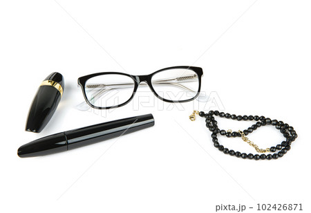 Lipstick, mascara, glasses and black beads isolated on white. Lipstick, mascara, glasses and black beads isolated on white. 102426871