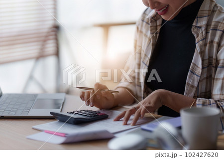 Asian accounting professional calculating household bills, reviewing and analyzing household bills, and filing tax returns. Asian accounting professional calculating household bills, reviewing and analyzing household bills, and filing tax returns. 102427620
