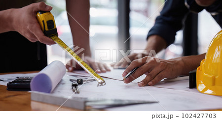Architect and Engineer working with blueprints for architectural plan, engineer sketching a construction project, green energy concept 102427703
