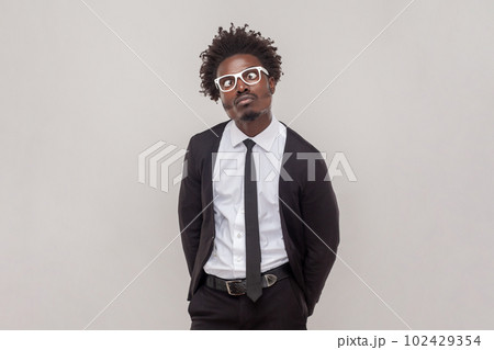 Portrait of funny comic man in glasses crosses eyes, pouts lips, makes grimace, foolishes after all day working, wearing white shirt and tuxedo. Indoor studio shot isolated on gray background. Portrait of funny comic man in glasses crosses eyes, pouts lips, makes grimace, foolishes after all day working, wearing white shirt and tuxedo. Indoor studio shot isolated on gray background. 102429354