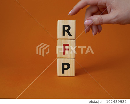 RFP - Request for Proposal. Wooden cubes with word RFP. Businessman hand. Beautiful orange background. Business and Request for Proposal concept. Copy space. 102429922