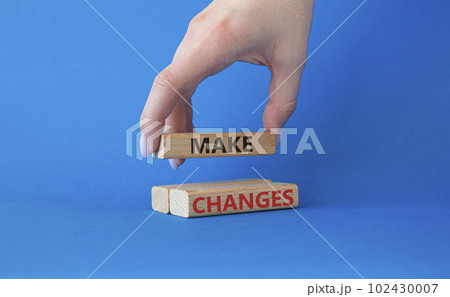 Make changes symbol. Wooden blocks with words Make changes. Beautiful blue background. Businessman hand. Business and Make changes concept. Copy space. 102430007