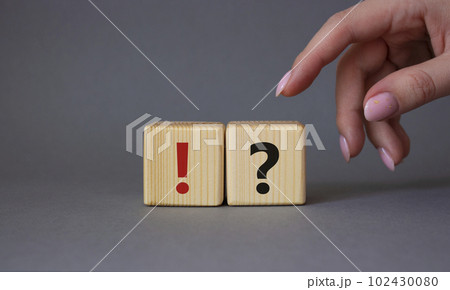 Question mark and exclamation mark symbol. Businessman hand is making a choice between Question mark and exclamation mark symbol. Beautiful grey background. Business concept. Copy space. 102430080