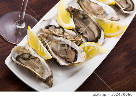 Opened raw oysters with lemon 102430660