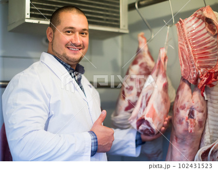 Smiling male shop staff cutting sirloin at top Smiling male shop staff cutting sirloin at top 102431523