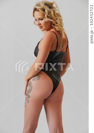 a sexy blonde with tattoos in a leather swimsuit. view from the back a sexy blonde with tattoos in a leather swimsuit. view from the back 102432722