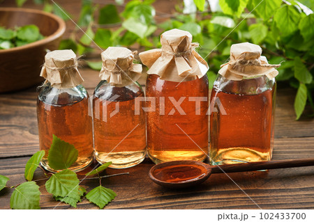 Bottles of birch essential oil, infusion or tincture. Birch syrup or coal tar oil bottles. Twigs of Birch tree with leaves. Alternative herbal medicine. 102433700