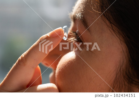 Close-up portrait caucasian woman putting on a contact lens.  102434151