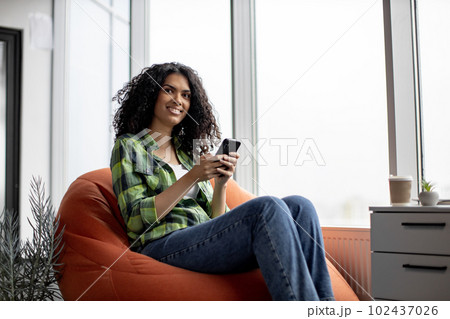 Woman chatting with colleagues via cell phone in office Woman chatting with colleagues via cell phone in office 102437026