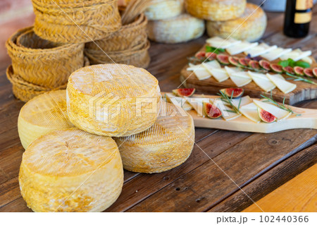 Wheels of hard goat cheese stacked on table during degustation 102440366