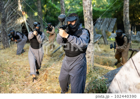 Impudent teams facing on battlefield in outdoor paintball arena during match 102440390