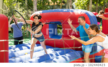 Cheerful woman having funny competition in collect of hoops on inflatable trampoline 102440423