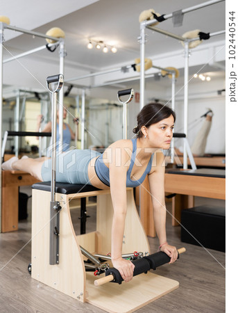 Young asian girl practicing pilates exercises on combo chair 102440544