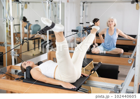 Side view of sports woman stretching body on pilates bed during workout 102440605