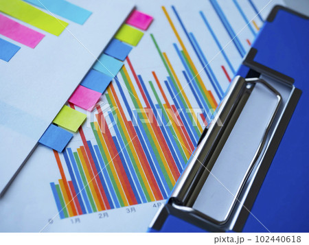 テーブルに置かれたバインダーとグラフ、付箋の付いた書類 102440618