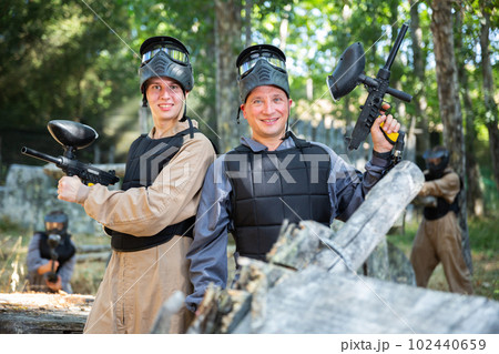 Portrait of positive man and teenage boy paintball players Portrait of positive man and teenage boy paintball players 102440659
