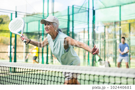 Mature woman playing padel tennis on court 102440681
