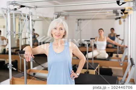 Smiling elderly woman leaning on wunda chair in pilates studio Smiling elderly woman leaning on wunda chair in pilates studio 102440706
