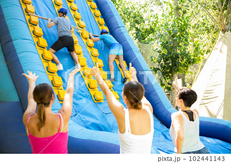 Two men climbing on inflatable castle with wooden sticks 102441143