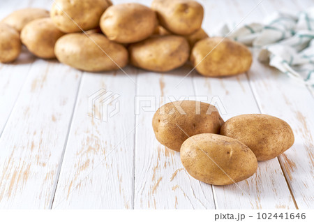 Raw yellow potatoes on a white wooden table, selective focus. Raw yellow potatoes on a white wooden table, selective focus. 102441646