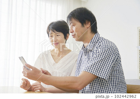 リビングでスマートフォンを使う熟年夫婦 102442962