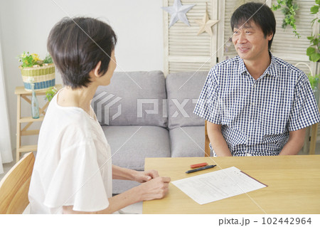 熟年結婚　婚姻届を挟んで座る中年男性と中年女性 102442964