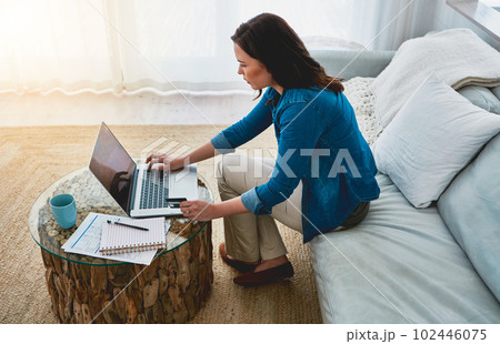 Shopping without leaving the house. High angle shot of an attractive young woman shopping online using her laptop. Shopping without leaving the house. High angle shot of an attractive young woman shopping online using her laptop. 102446075
