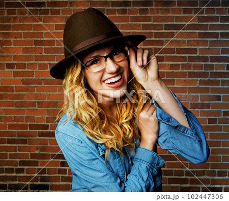 I see this life and Im loving it. a beautiful and trendy young woman posing against a brick wall. 102447306