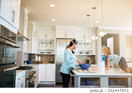 Please add extra chocolate chips to the cookies, Mom. a little boy watching his mother bake cookies at home. 102447953