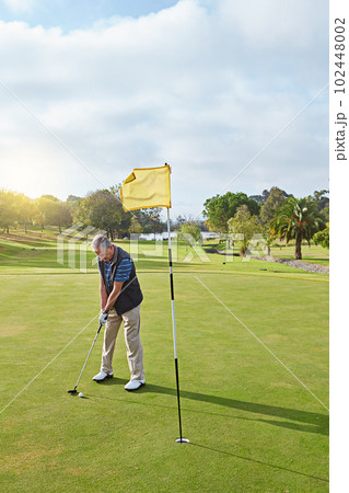 Lining up the shot. Full length shot of a senior man lining up a put while enjoying a day playing golf. 102448002