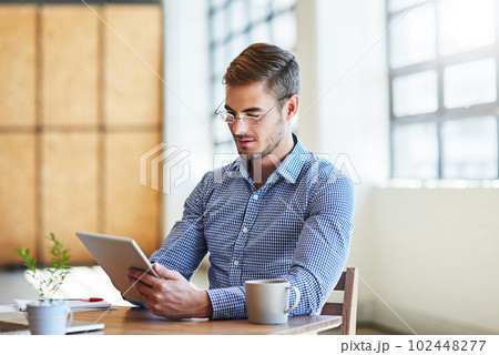 Managing his business network with modern technology. a young businessman using a digital tablet in an office. Managing his business network with modern technology. a young businessman using a digital tablet in an office. 102448277